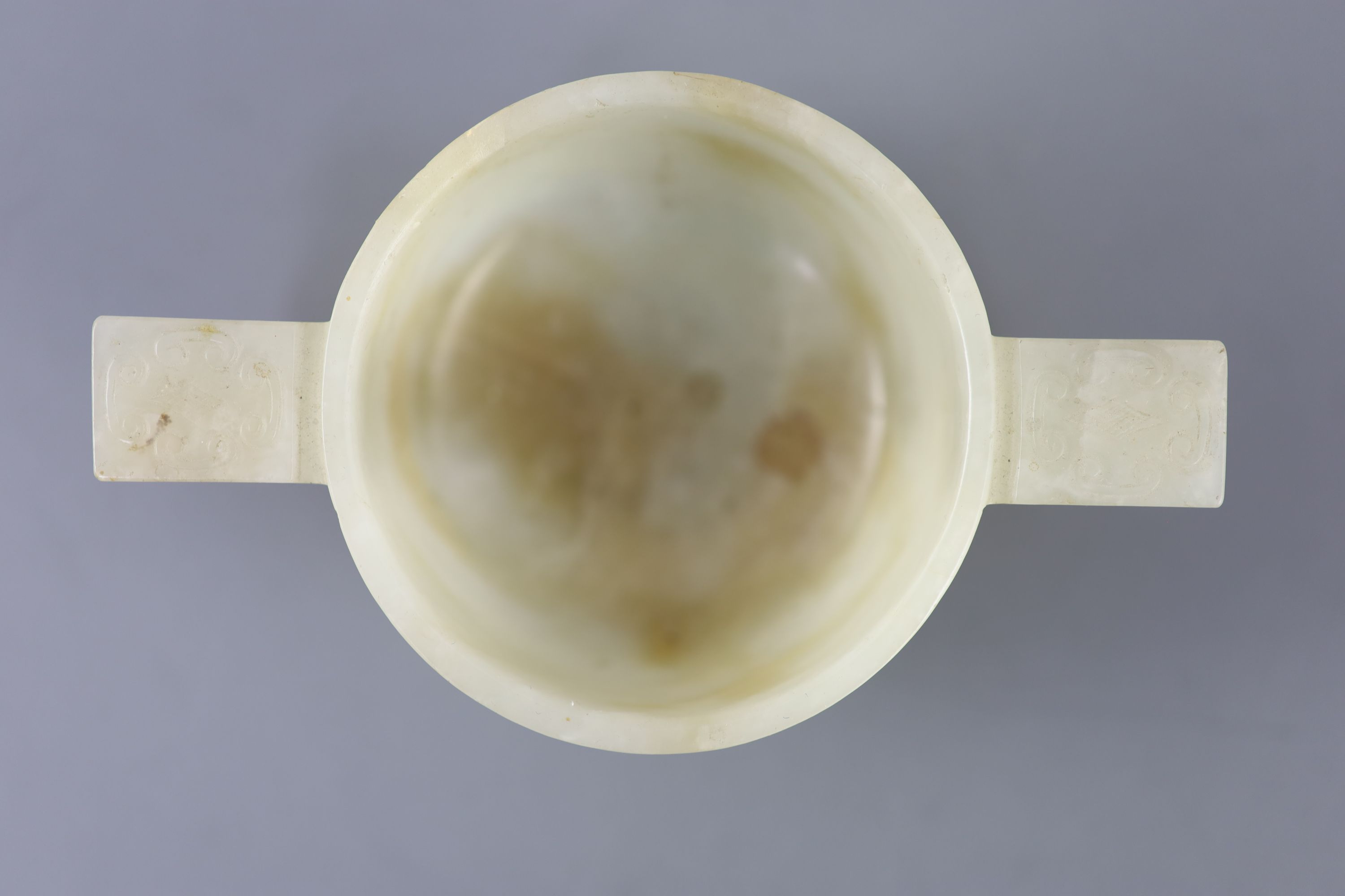 A Chinese pale celadon and russet jade cup, 17th/18th century, 12.5cm wide